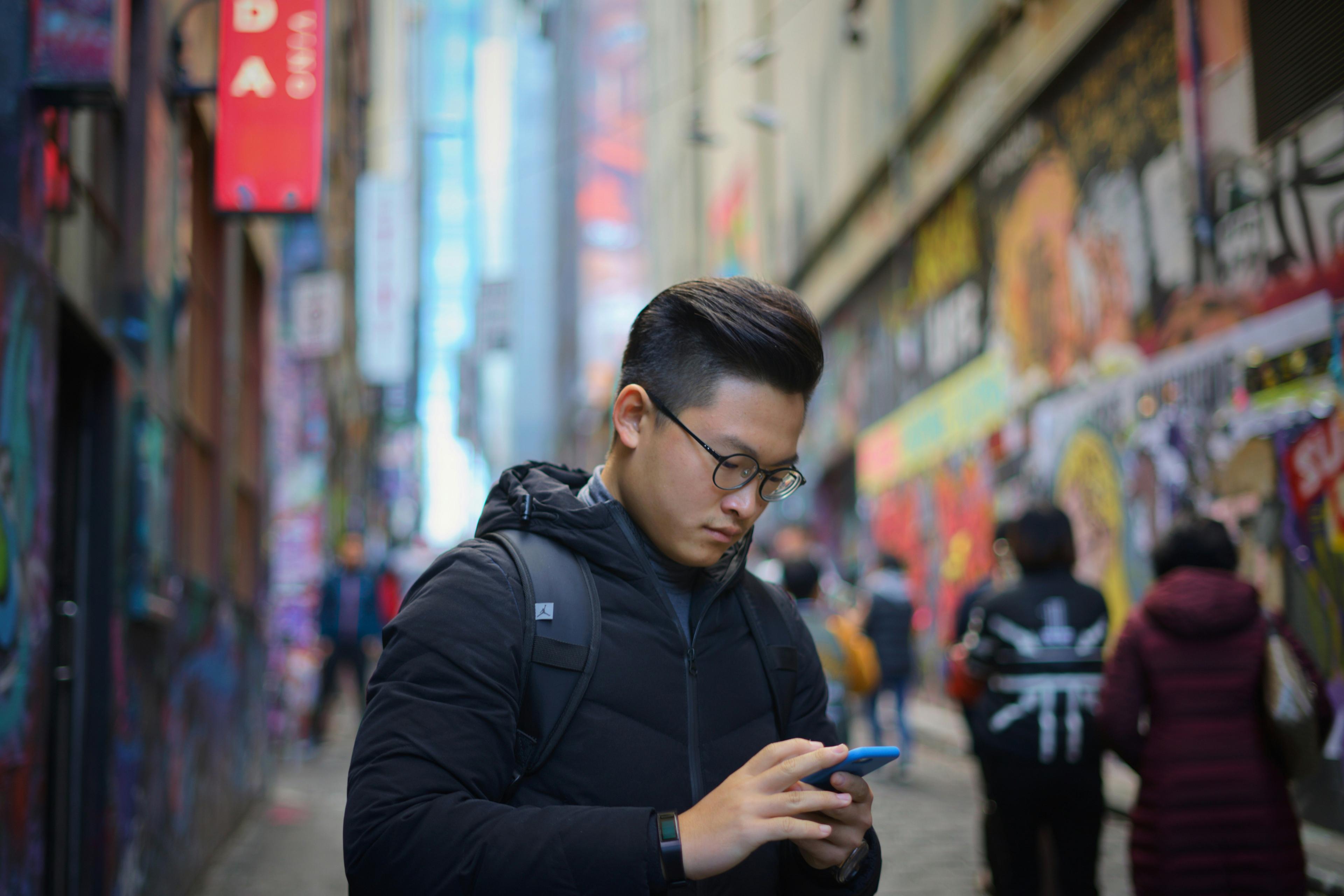 Seorang lelaki merakam idea pada telefon sambil berjalan di lorong bandar